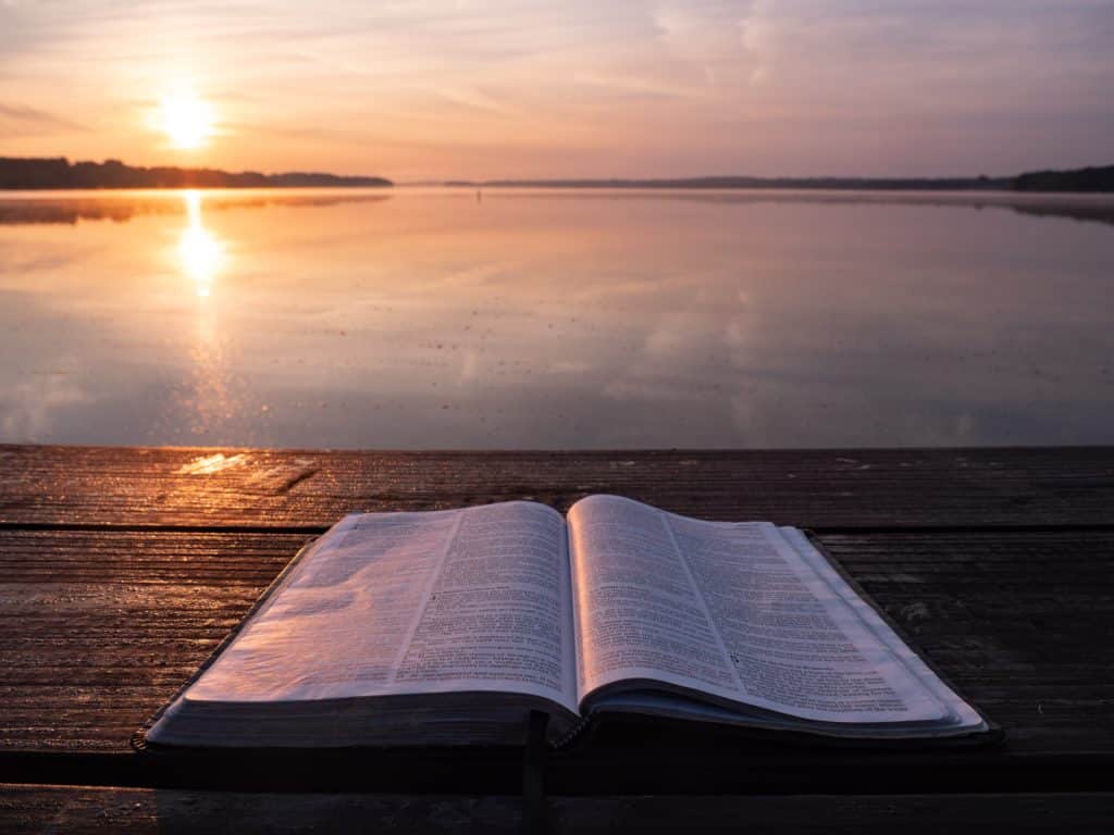 image of an open bible with a suset at the side of a lake