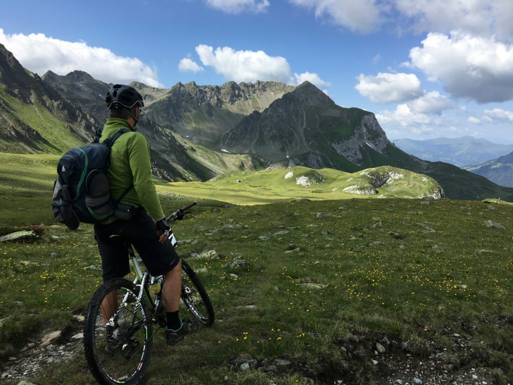 jeunse sur velo de montagne, photo pris de dos, le jeune regarde un magnifique panorama avec une montagne dans la distance.  illustre les camp pour jeunes (camps JABs) en Suisse,  en particulier les camps vélos.