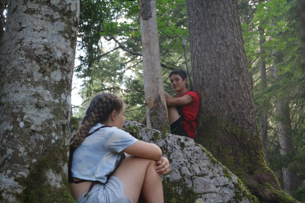 2 enfants qui jouent dans la forêt lors d'un camp pour enfants Jeunesse avec activités de montagne / nature.