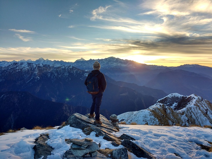 jeune qui regarde un paysage d'hiver, avec des montagnes pleines de neige