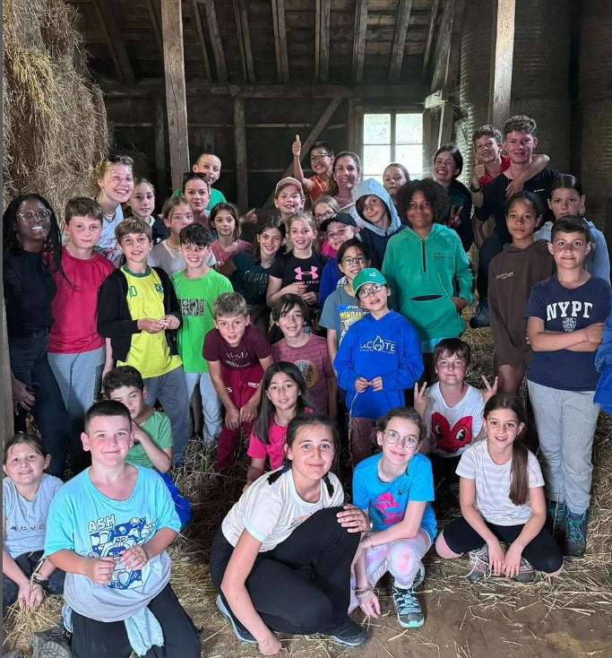 jeunes enfants pendant une sortie à une ferme pendant un camp de vacances d'été; children during a summer camp. Excursion to the farm, photo taken in the barn with hay stacks.