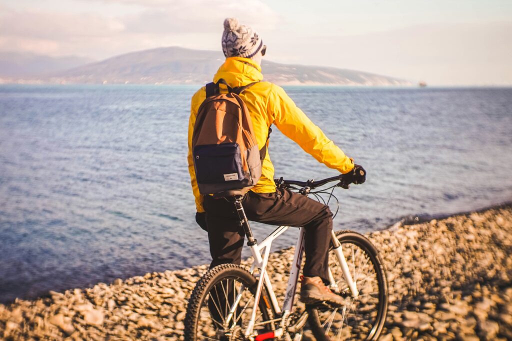 
biker taking a break by the lake looking at the mountains in the distance