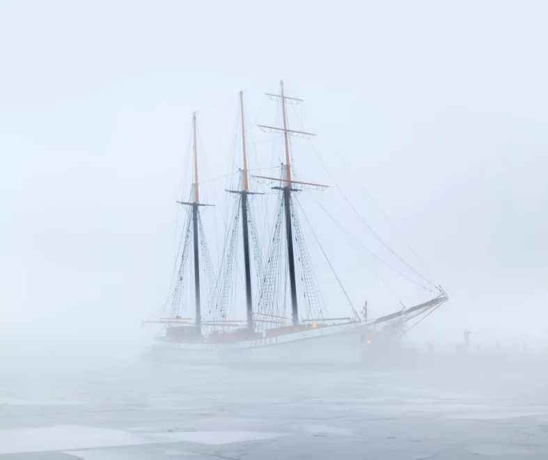 An illustration of a sailboat on a frozen lake in winter, representing the KidsTeam Lausanne-Renens theme, "The Lake Navigators in Winter." The scene evokes calm yet strength as the sailboat, symbolizing resilience and faith, sits ready to face life's "winter storms."