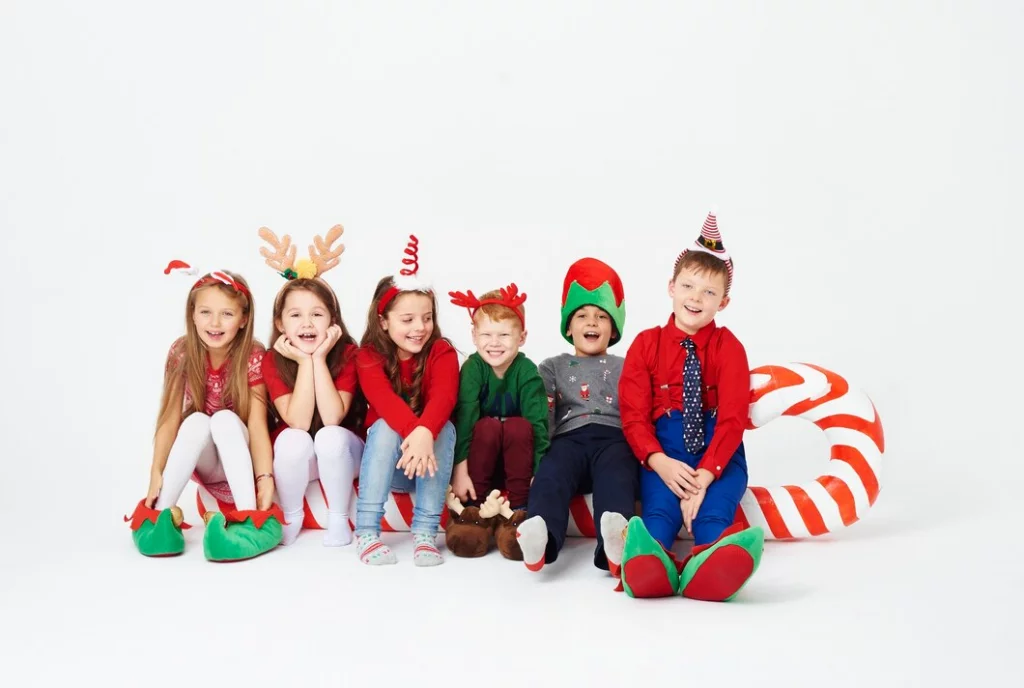 A joyful group of children from KidsTeam Lausanne – Renens creating Christmas crafts and sharing snacks in a cozy, festive setting decorated with holiday lights, embodying the spirit of togetherness and creativity as they prepare for the season."